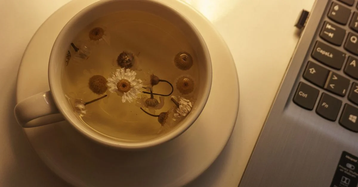 Una taza reconfortante de té de manzanilla junto a un portátil, perfecta para relajarse o para pausas en el trabajo.