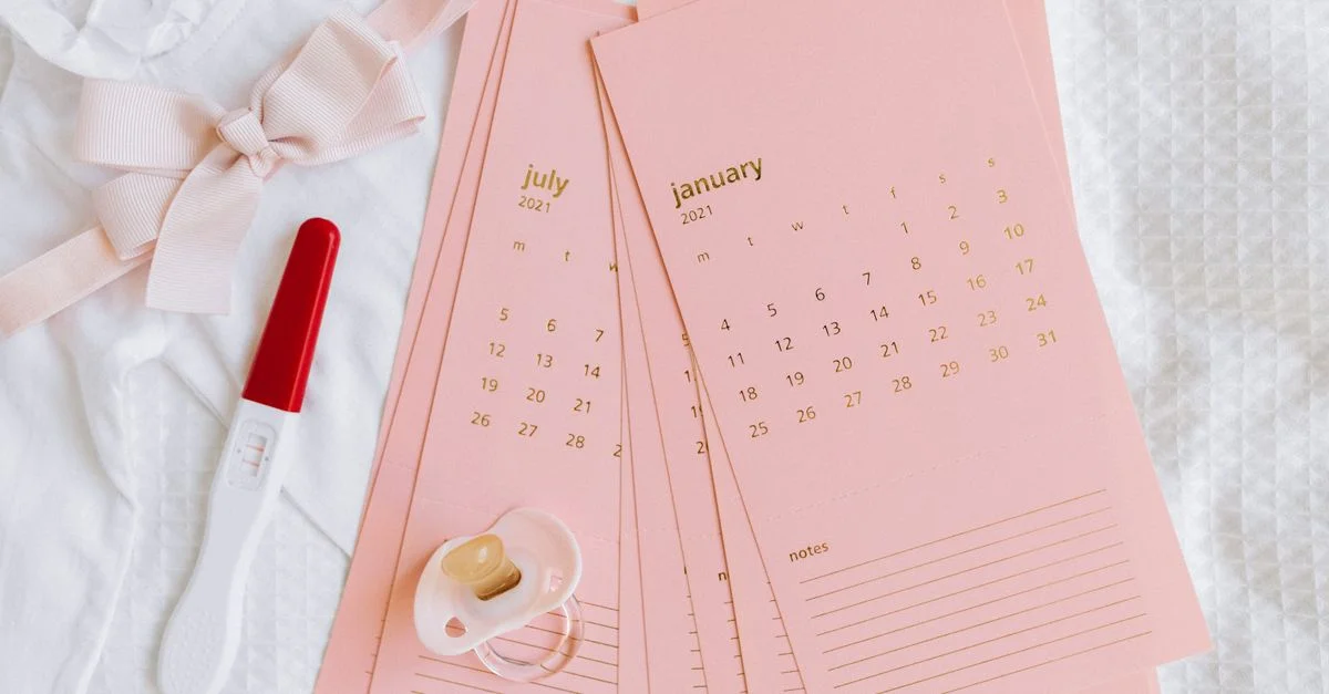 Disposición plana de prueba de embarazo, tarjetas de calendario y artículos de bebé que simbolizan nuevos comienzos.