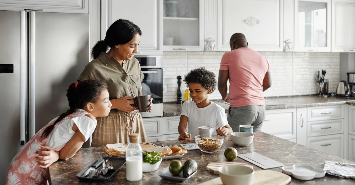 Una familia preparando el desayuno junta en un acogedor ambiente de cocina, mostrando la unión y la rutina matutina.