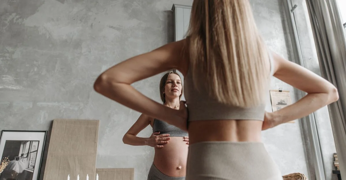 Mujer embarazada practicando yoga en interiores, enfocándose en un estilo de vida saludable y ejercicio.