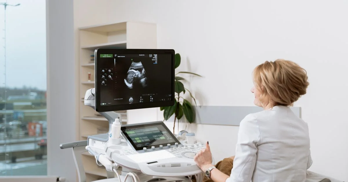 Médico realizando una ecografía prenatal con equipo médico en una clínica.