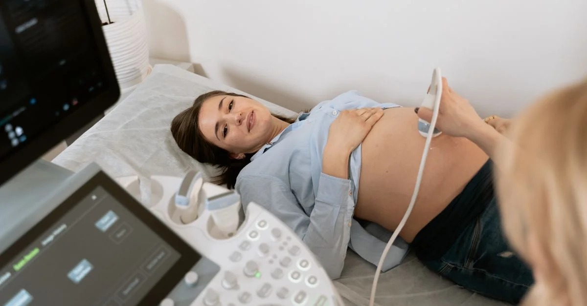 Mujer embarazada sometiéndose a una ecografía, asistida por un profesional de la salud en una clínica médica.