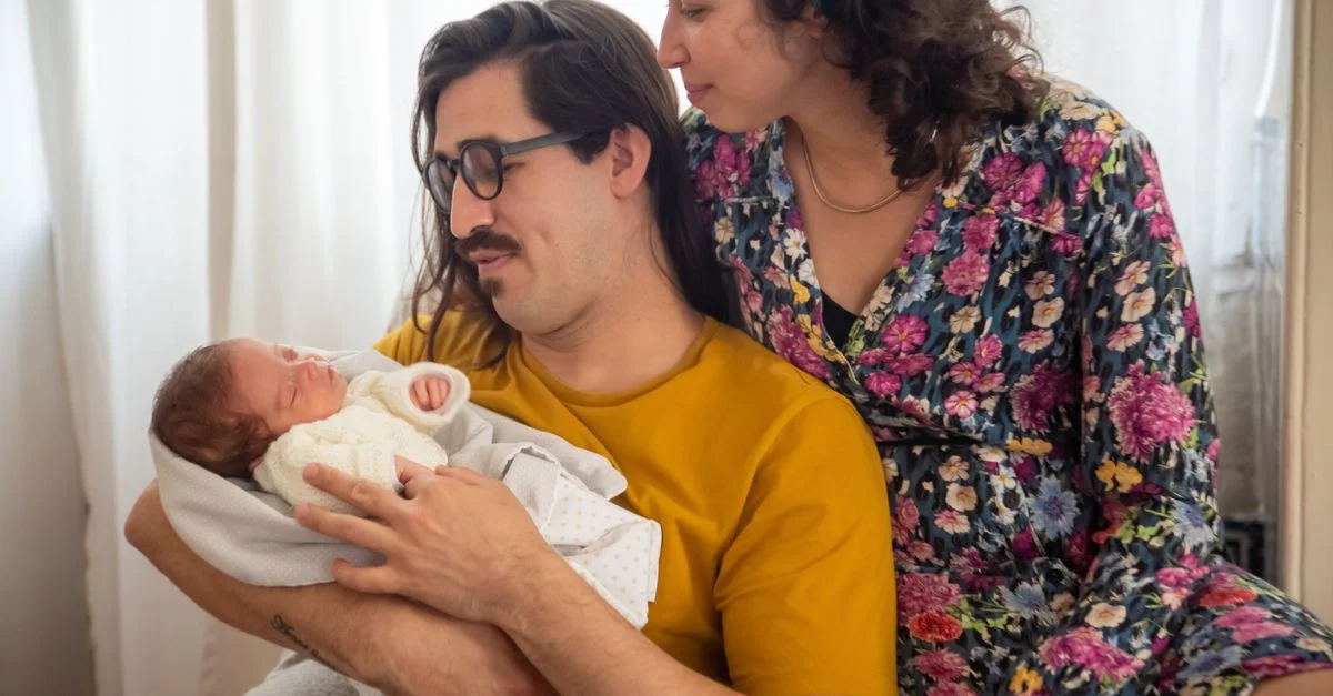 Retrato familiar conmovedor que presenta a los padres sosteniendo amorosamente a su recién nacido, capturando momentos tiernos.