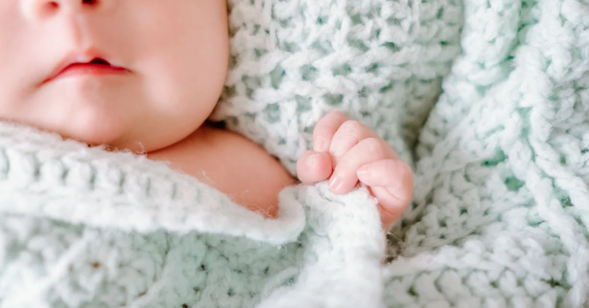 Adorable bebé recién nacido envuelto en una acogedora manta de lana, capturando la inocencia pacífica.