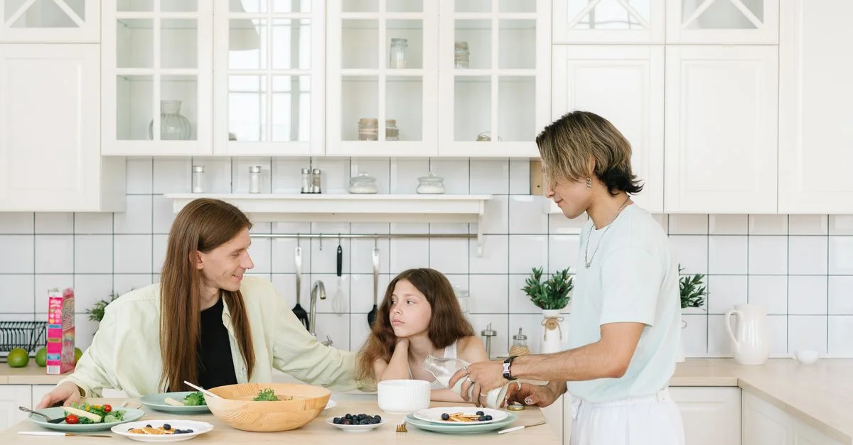 Una familia disfruta del desayuno junta en un entorno de cocina moderno y brillante.