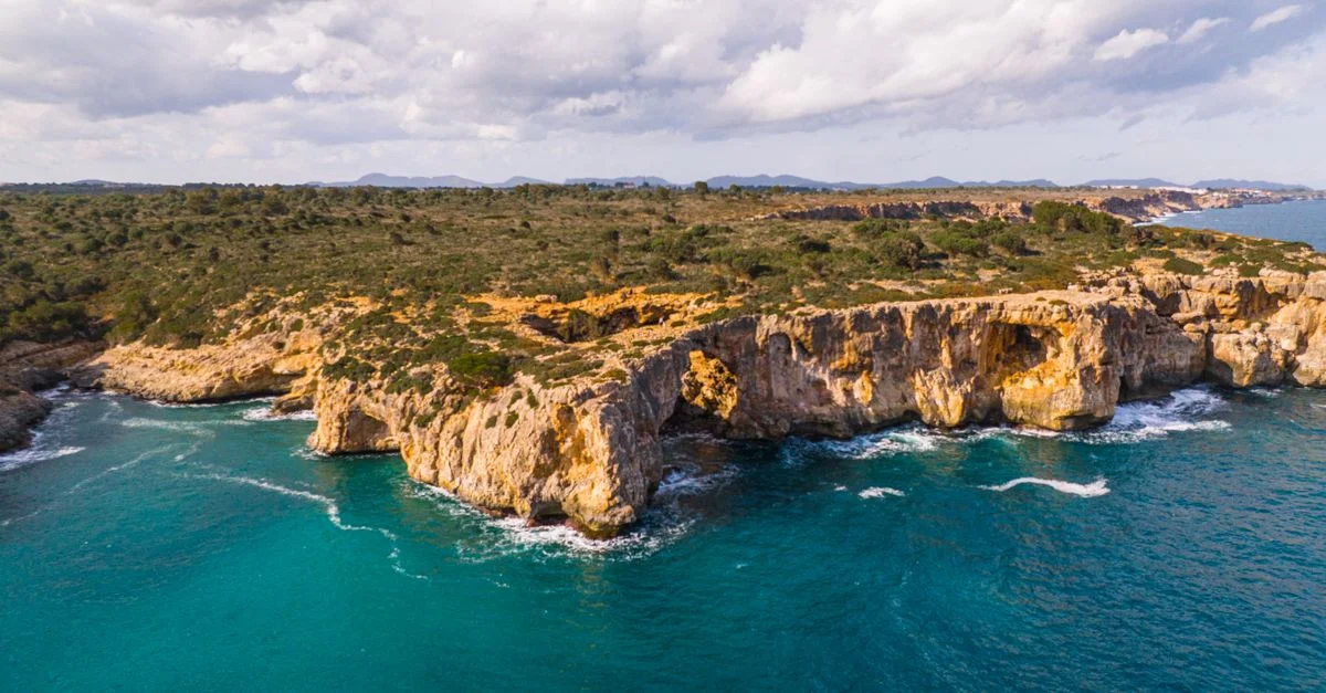 Une vue aérienne à couper le souffle des falaises rocheuses et de la mer turquoise à Majorque, Espagne, sous un ciel ensoleillé.