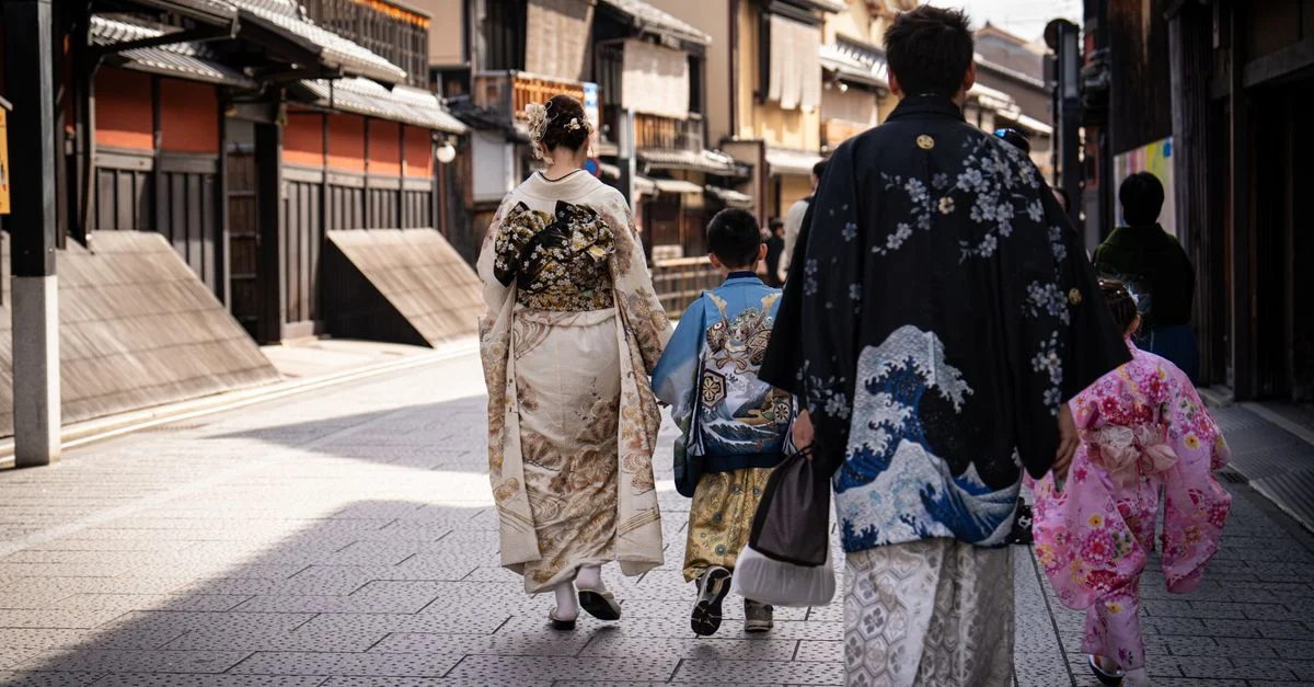Una familia japonesa con kimonos coloridos caminando por una calle histórica en Kioto, Japón.