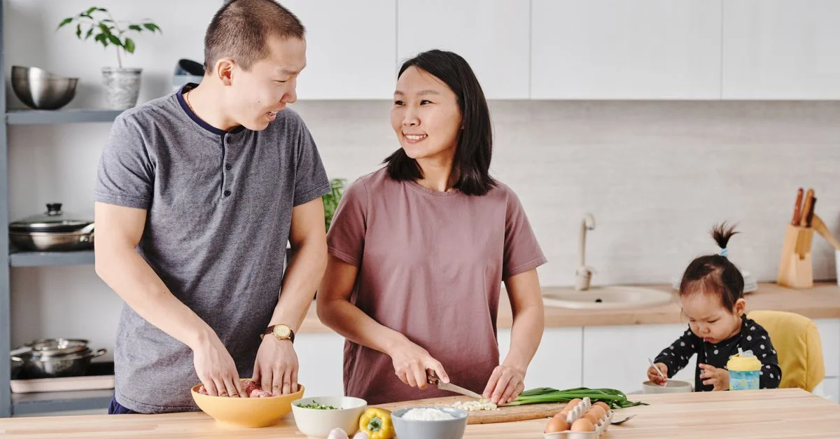 Familia asiática disfrutando de la cocina juntos en una cocina moderna, fomentando la unión y el amor.