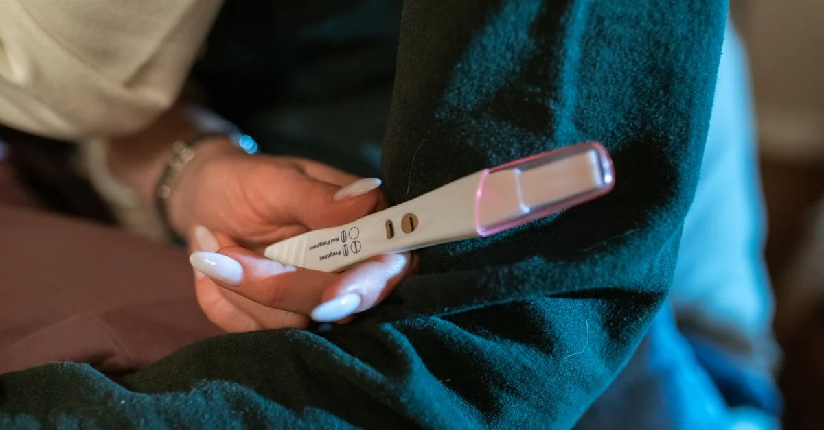 La mano de una mujer sosteniendo un test de embarazo positivo, simbolizando esperanza y nuevos comienzos.
