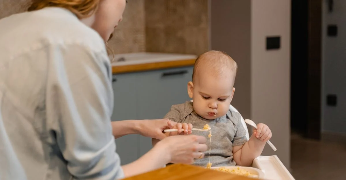 Una madre alimenta amorosamente a su bebé en un cálido y acogedor entorno de cocina en casa.