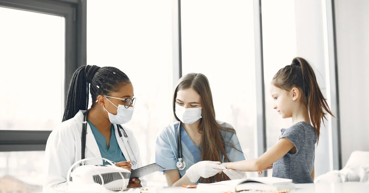 Des professionnels de la santé s'occupant d'un enfant à l'intérieur lors d'un contrôle médical.